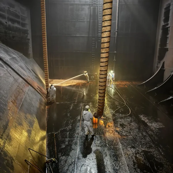 marine tank cleaning crew performing cargo tank cleaning with high-pressure washing system on ship